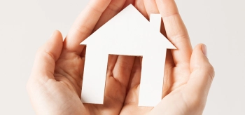 Hands holding paper house