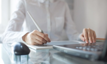 Business Frau am Schreibtisch vor dem Laptop und iPad