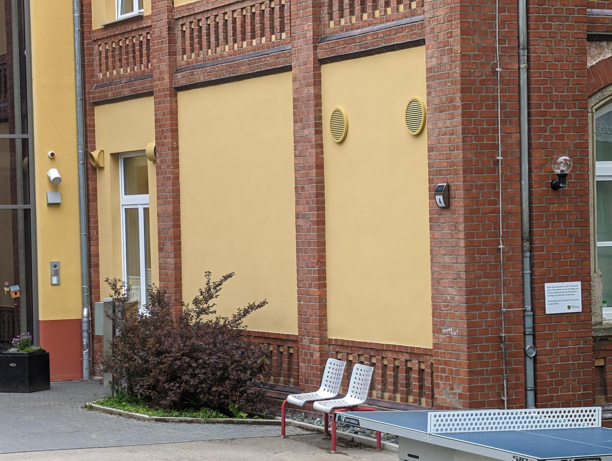Fassade mit gelb lackierten Außen- und Fortluftgittern AR637