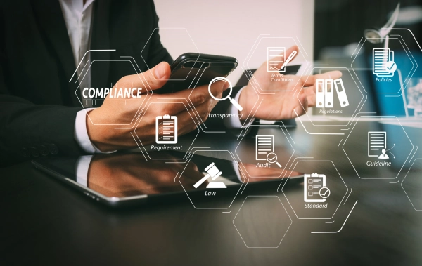 Business Mann mit Smartphone und Ipad am Tisch mit Icons zu Normen, Richtlinien und Gesetzen