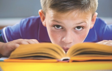 Schulkind mit aufgeschlagenem Buch