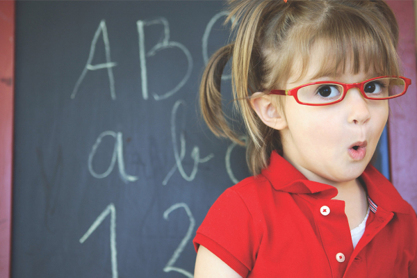 Schulmädchen mit Brille vor einer Tafel